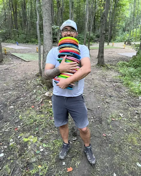 Tets holding a huge stack of discs on a wooded course